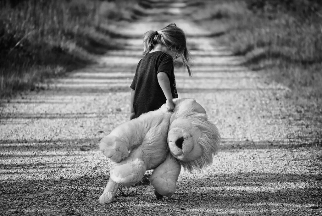 an unhappy girl dragging a teddy bear 