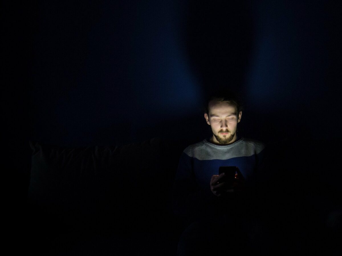 man using phone in darkness