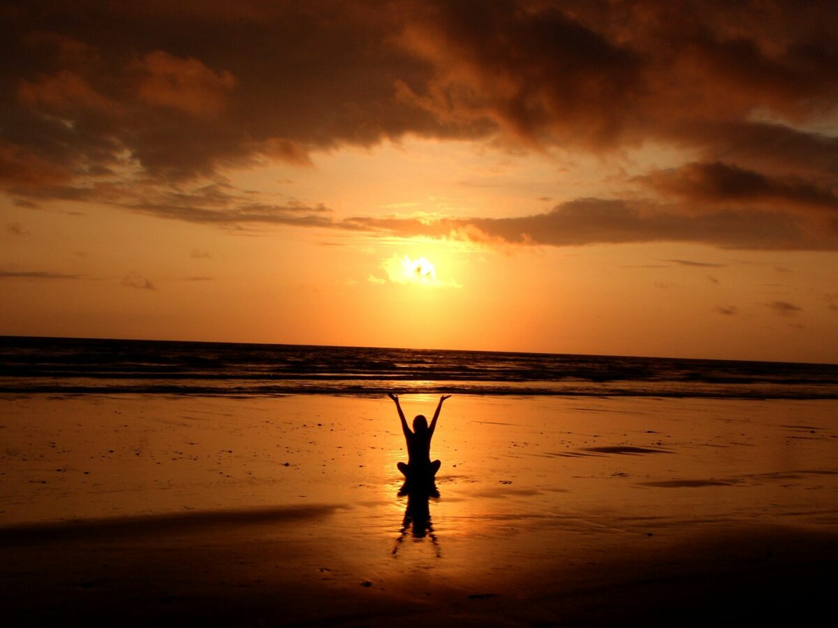 man raising hands in front of sunset